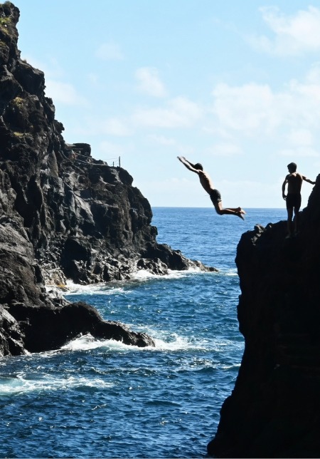 Boys jumping from a cliff into the sea